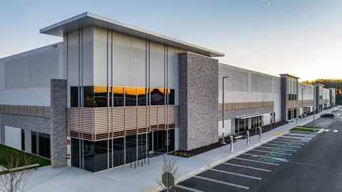 Modern flex-industrial building with surface parking lot, a development typology directly shaped by municipal parking minimums and FAR regulations.