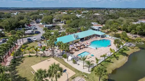 Aerial view of an RV resort with a pool and clubhouse beside a lake in Florida
