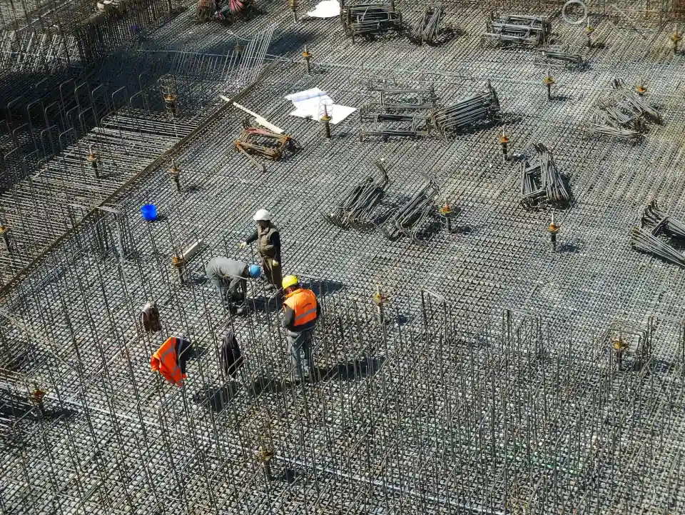 Workers tie rebar across a foundation mat before a concrete pour, the moment a permit becomes a housing start.