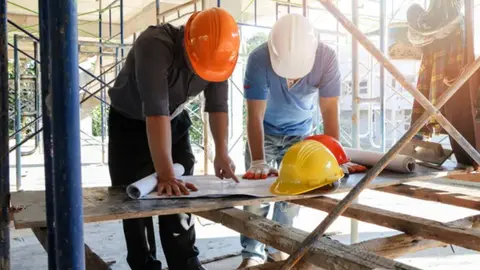 Construction managers analyzing site plans to address cost escalation and bid pricing