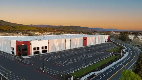 Aerial view of a newly completed commercial industrial facility showing key site plan elements evaluated by lenders, parking lot striping, fire lane curbing, landscaping buffers, ingress/egress circulation, and setback compliance against adjacent residential development.