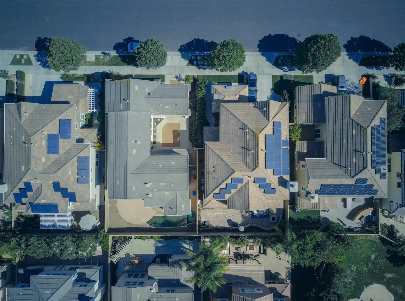 Aerial view of modern suburban homes with rooftop solar panels, showcasing energy-efficient design and sustainable building practices.