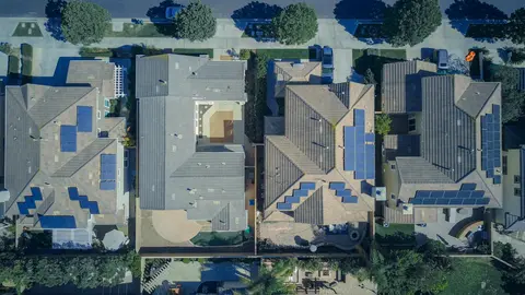 Aerial view of modern suburban homes with rooftop solar panels, showcasing energy-efficient design and sustainable building practices.
