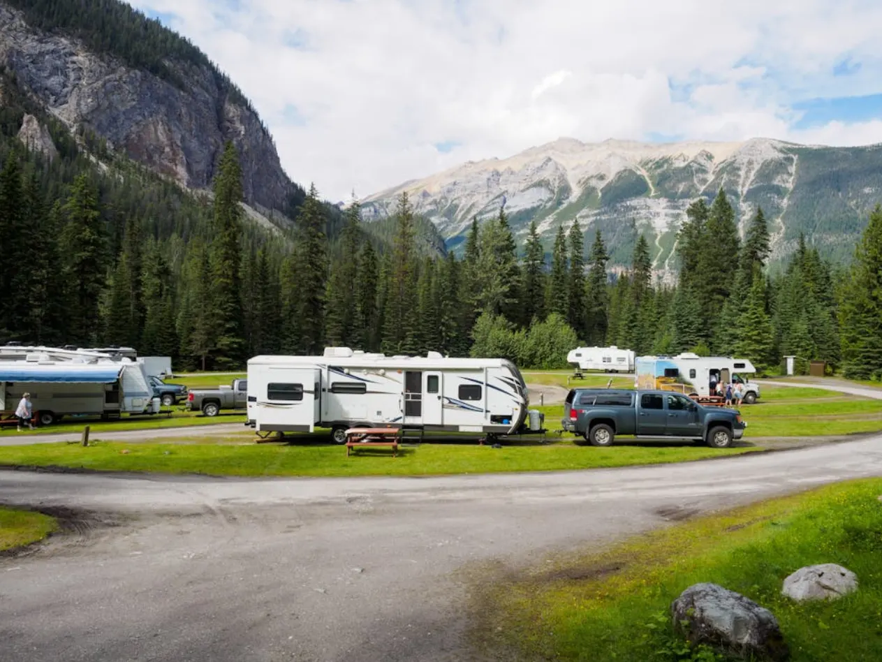 Scenic RV park with trailers surrounded by mountains and pine trees