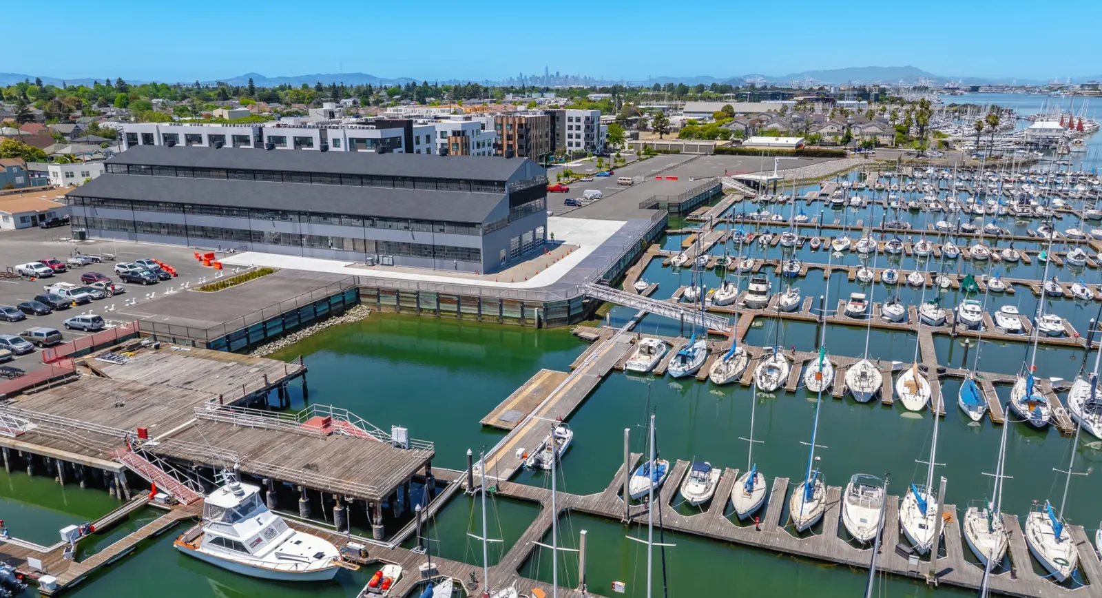 Aerial view of a California Bay Area marina showing wet slip configuration, finger pier layout, and adjacent waterfront commercial development, illustrating the USACE Section 10 and CCC coastal permitting environment for mixed-use marina projects.