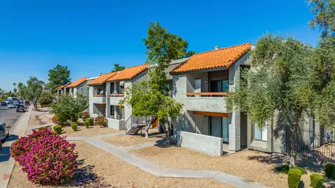 Two-story garden-style multifamily complex with surface parking and xeriscape landscaping, illustrating low-density residential development cost basis per acre.