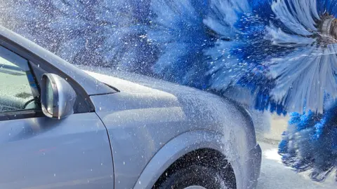 Vehicle passing through an express car wash tunnel conveyor