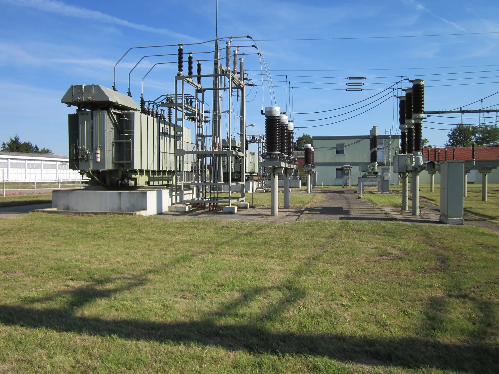 An electrical substation with transformers and steel gantries sitting in open grass, well back from the property edge.