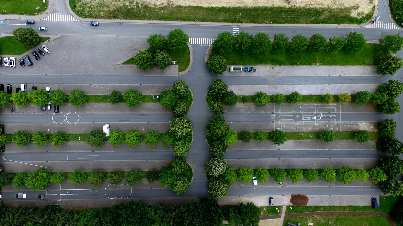 A commercial parking field seen from directly above, with landscaped strips between the aisles.